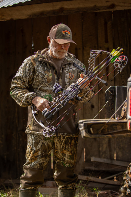 Man wearing the Non-Typical Endurance Hooded Full Zip Jacket with Scent Control, holding a bow, demonstrating its flexibility and functionality for hunting.