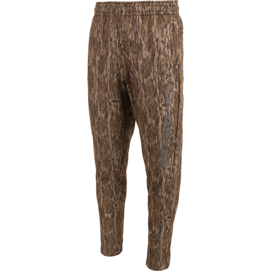 Drake Under-Wader Jogger with camouflage pattern, featuring front slash pockets, hook and loop closure rear pockets, and tapered legs for secure fit under waders.