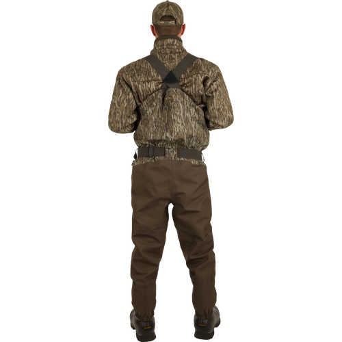 A man in camouflage clothing wearing the Guardian Elite Hybrid Insulated Front Zip Wader, showcasing its advanced features for serious outdoor activities.