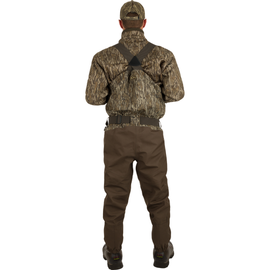 A man in camouflage clothing wearing the Guardian Elite Hybrid Insulated Front Zip Wader, showcasing its advanced features for serious outdoor activities.