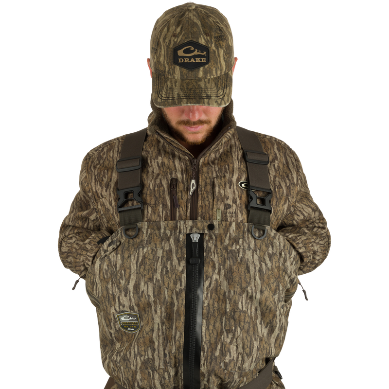 Man wearing Guardian Elite Hybrid Insulated Front Zip Wader with camouflage jacket and hat, showcasing advanced features like TiZIP® zipper and reinforced seams for high-performance hunting.