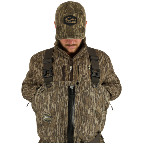 Man wearing Guardian Elite Hybrid Insulated Front Zip Wader with camouflage jacket and hat, showcasing advanced features like TiZIP® zipper and reinforced seams for high-performance hunting.