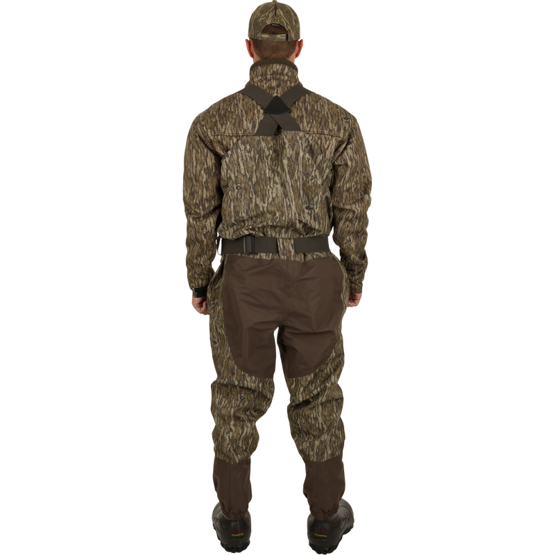 A man in camouflage clothing wearing Insulated Guardian Elite Vanguard Breathable Waders - Old School, featuring 100% waterproof fabric, LokDown insulation, and Thinsulate Buckshot Mudder boots.