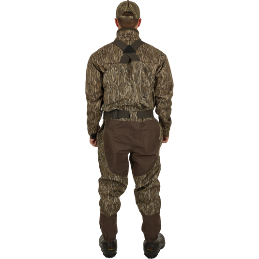 A man in camouflage clothing wearing Insulated Guardian Elite Vanguard Breathable Waders - Old School, featuring 100% waterproof fabric, LokDown insulation, and Thinsulate Buckshot Mudder boots.