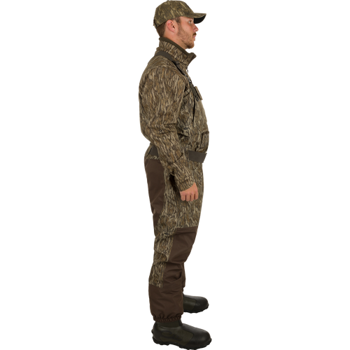 A man in camouflage clothing and hat, wearing Insulated Guardian Elite Vanguard Breathable Waders by Drake Waterfowl for hunting. Waterproof, windproof, 3-layer fabric with LokDown insulation and Thinsulate boots.