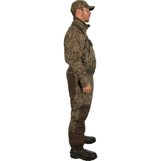 A man in camouflage clothing and hat, wearing Insulated Guardian Elite Vanguard Breathable Waders by Drake Waterfowl for hunting. Waterproof, windproof, 3-layer fabric with LokDown insulation and Thinsulate boots.