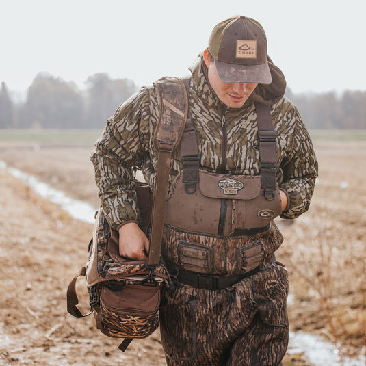 Buckshot Eqwader 1600 Neoprene Wader 3.0: A man in camouflage gear with a hat and backpack, showcasing the durable, waterproof wading system in a field.