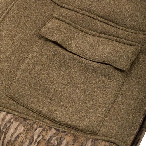 Close-up of a Silencer Bib pocket, showcasing durable fabric and vertical zippered storage designed for hunting gear.