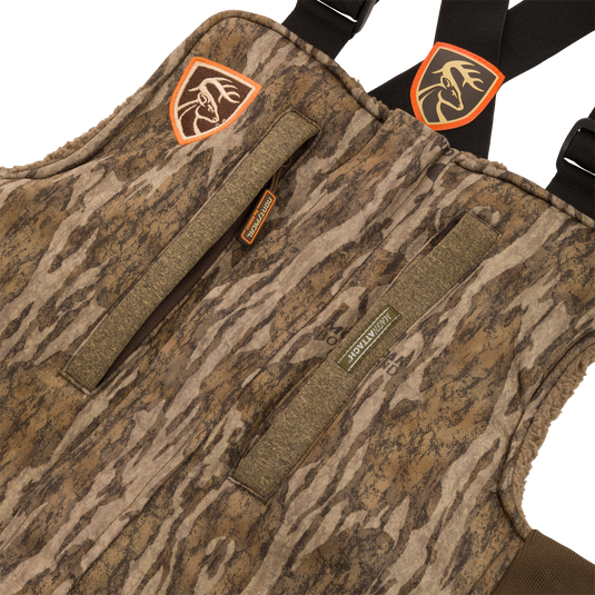 Close-up of the Silencer Bib with a visible zipper and deer head patch, showcasing its durable fabric and practical pockets for hunting gear.