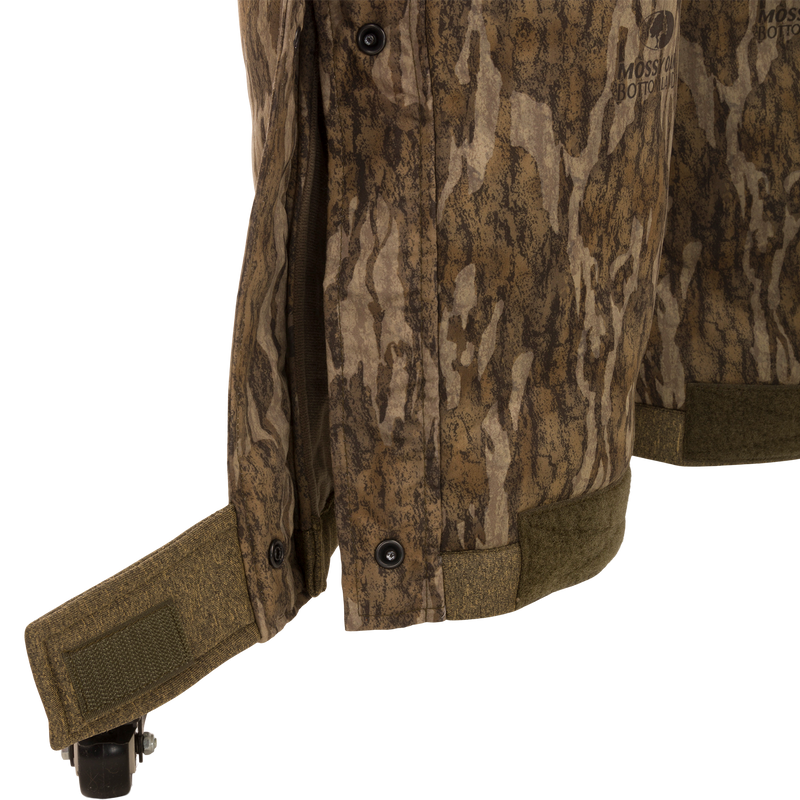 Close-up of the Silencer Bib camouflage jacket showing its durable fabric and vertical zippered chest pocket with removable lanyard.