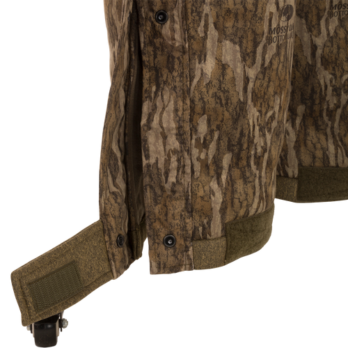 Close-up of the Silencer Bib camouflage jacket showing its durable fabric and vertical zippered chest pocket with removable lanyard.