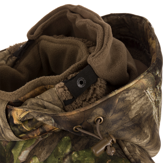 Close-up of the Stand Hunter's Silencer Jacket with Scent Control, highlighting the durable outer fabric, metal rings, and various pockets for hunting gear.