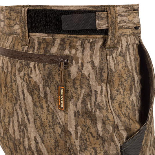 Close-up of EST Camo Tech Stretch Pants with Scent Control, showing camouflage fabric, zippered pockets, and adjustable waistband. Ideal for versatile hunting conditions.