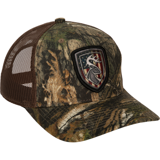 Americana Shield Patch Mesh-Back Cap with deer head and flag patch, breathable mesh back, lightly structured cotton twill front, and adjustable snap closure.