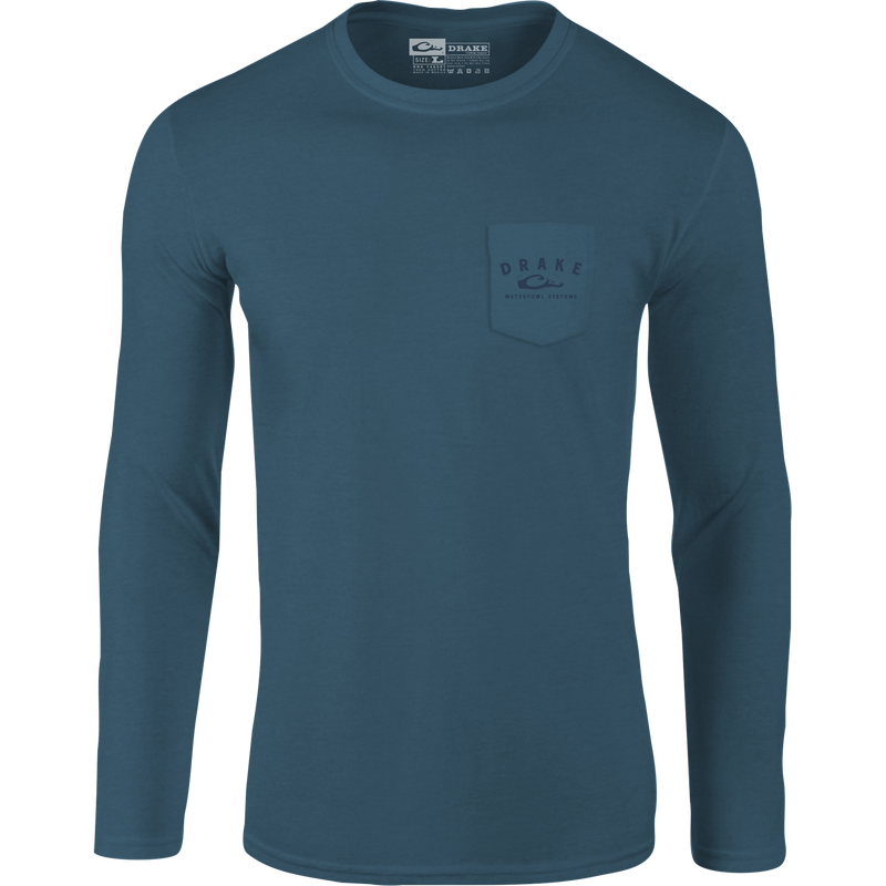 A Drake Waterfowl Graphic Tee featuring the Old School In Flight design, showcasing ducks in flight on a long-sleeved blue shirt with a logo pocket. Made of 60% cotton and 40% polyester for comfort.