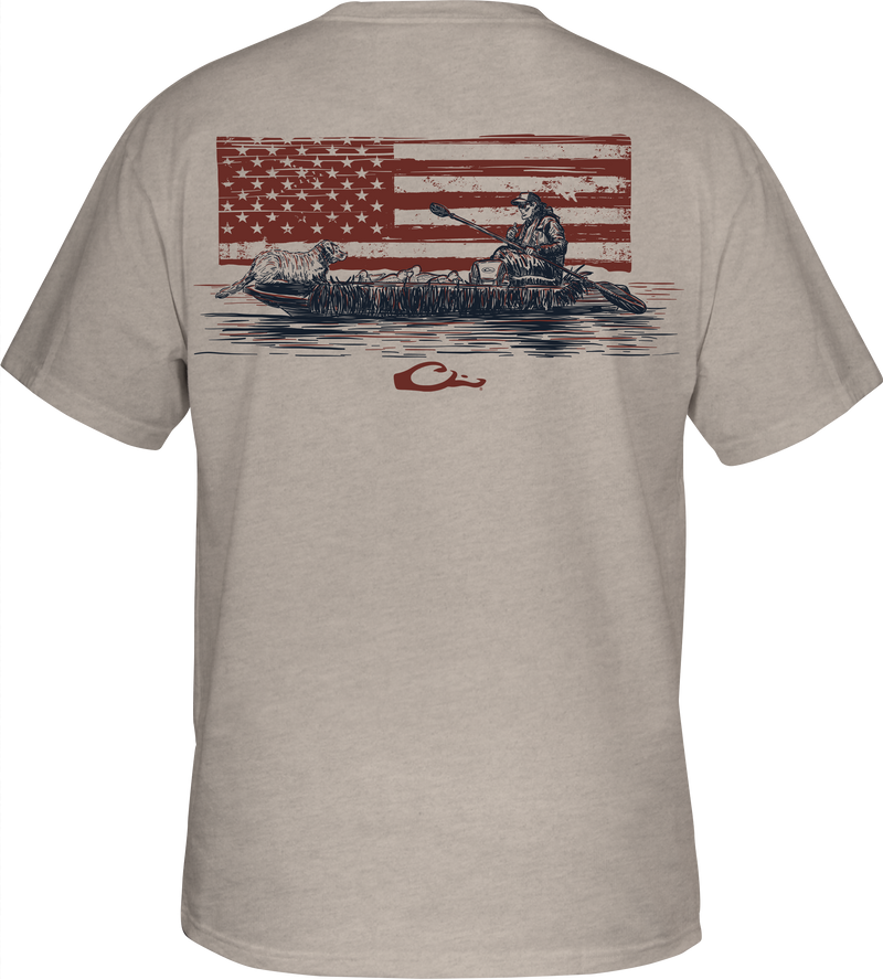 Kayak Flag T-Shirt featuring a man in a canoe with a dog and American flag graphic, part of Drake's Americana Series, known for hunting gear.