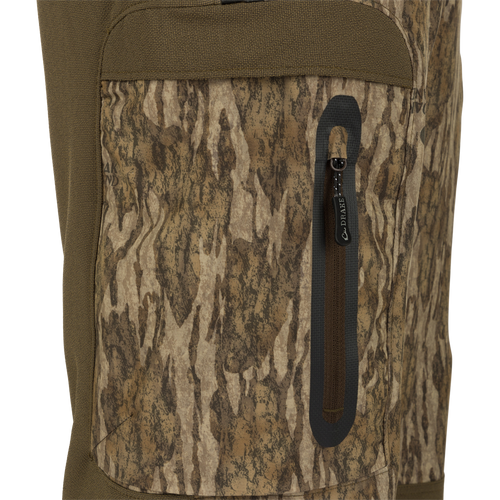 Close-up of MST Tech Stretch Bibs showing camouflage fabric, zippered leg pocket, and sturdy construction details. Ideal for versatile, comfortable hunting gear.