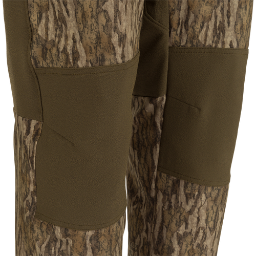 MST Tech Stretch Bibs with camouflage pattern featuring multiple zippered pockets, reinforced knees, and adjustable elastic shoulder straps.