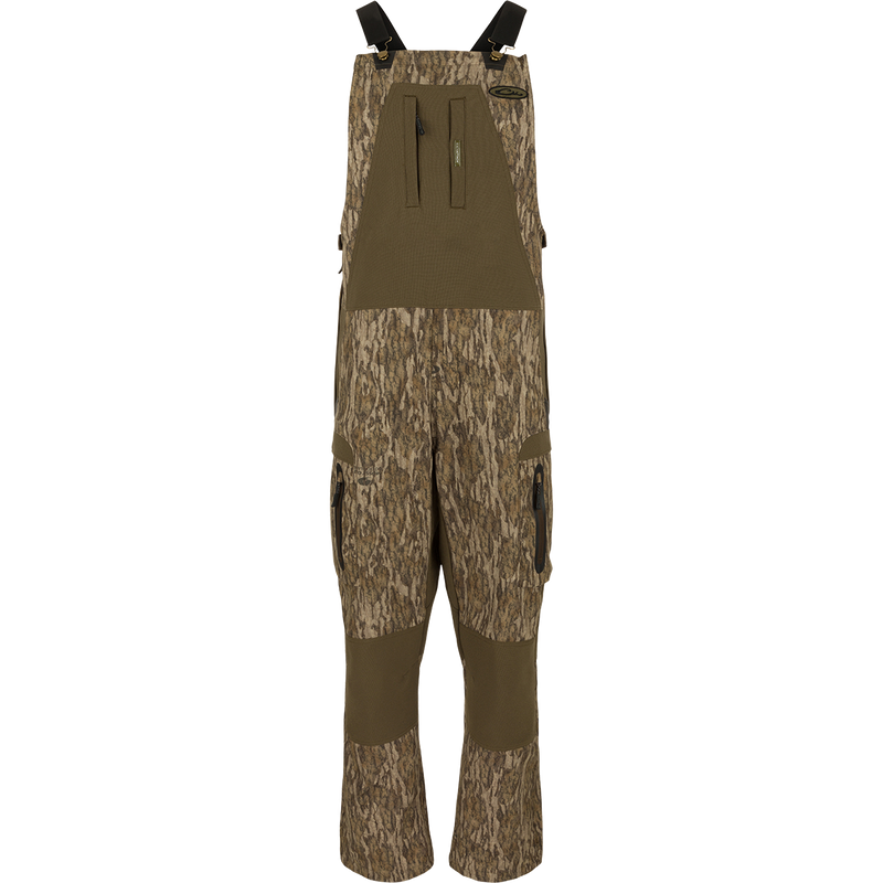 MST Tech Stretch Bibs with camouflage pattern, featuring elastic shoulder straps, multiple zippered pockets, and reinforced knees and seat for hunting and outdoor activities.