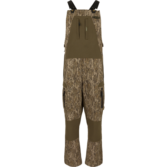 MST Tech Stretch Bibs with camouflage pattern, featuring elastic shoulder straps, multiple zippered pockets, and reinforced knees and seat for hunting and outdoor activities.