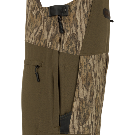 MST Tech Stretch Bibs with camouflage pattern, featuring front slash pockets, zippered leg pockets, and reinforced knees for hunting activities.