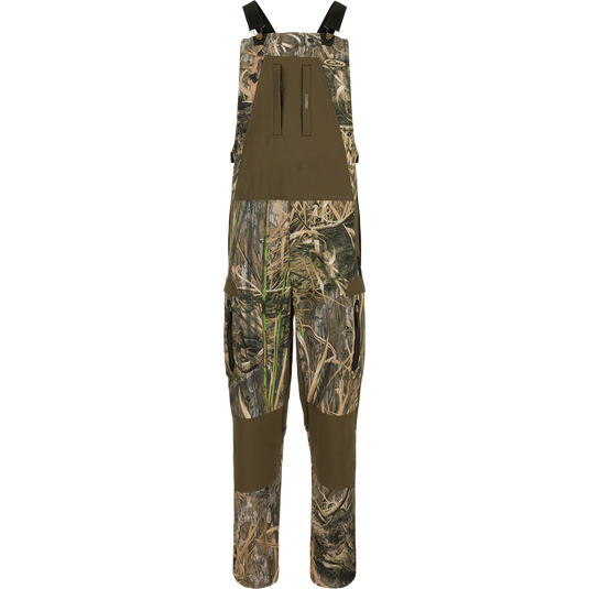 MST Tech Stretch Bibs with camouflage pattern, featuring elastic shoulder straps, multiple zippered pockets, reinforced knees, and silicone inner waistband for hunting versatility.