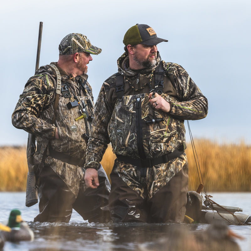 Men in camouflage gear, standing in water, wearing the Technical Performance Fleece Full Zip Jacket, showcasing its outdoor utility in hunting scenarios.