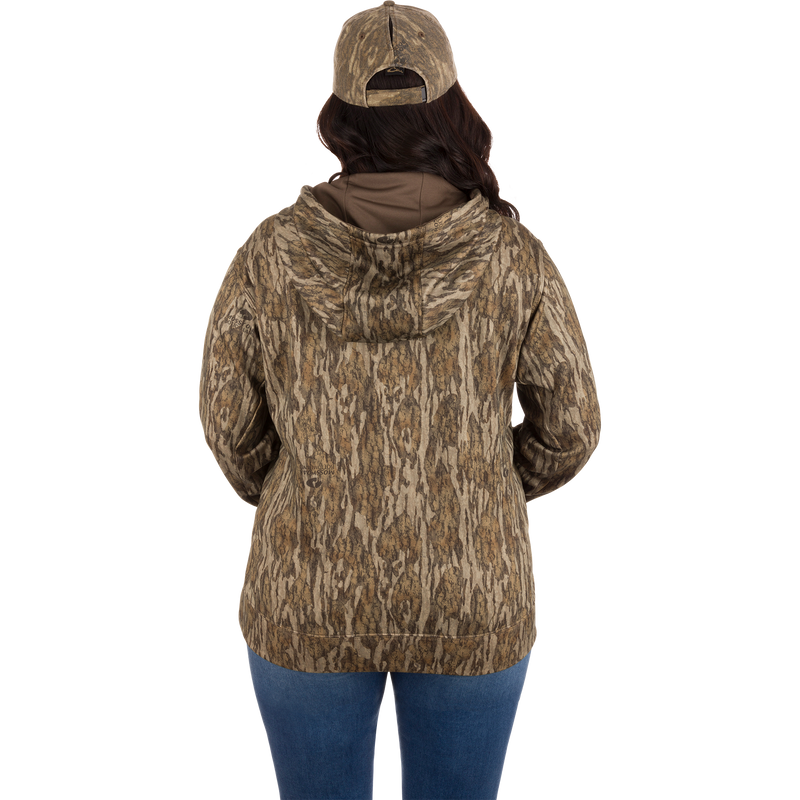 Woman wearing the Women's MST Performance Hoodie with double-lined hood, kangaroo pouch, and soft combed fleece interior, styled for everyday and field use.