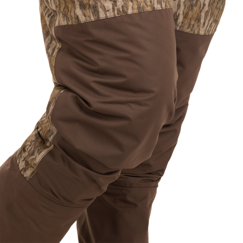 Person wearing Women’s Insulated Guardian Elite Vanguard Breathable Waders, featuring camouflage design, reinforced seams, and insulated liner for warmth and durability in cold hunting conditions.