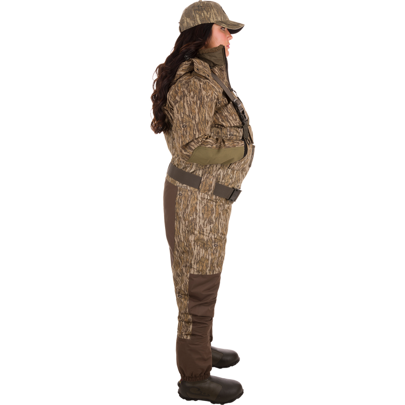 Woman wearing Women’s Insulated Guardian Elite Vanguard Breathable Waders with camouflage pattern, showcasing reinforced seams, cargo pouch, and insulated Thinsulate Buckshot Mud boots.