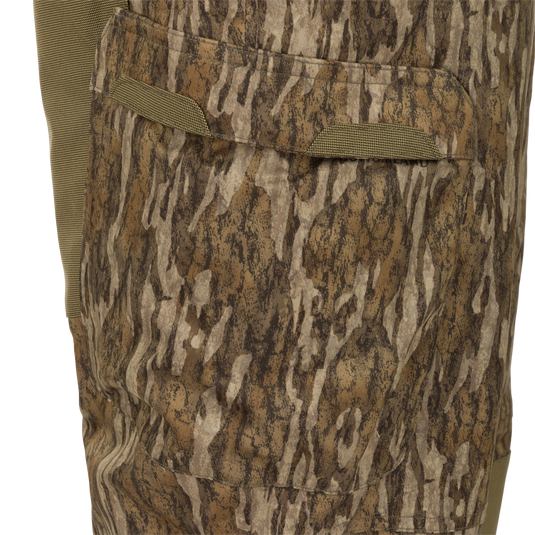 Close-up of MST Waist-High Insulated Bibs showcasing camouflage fabric with zippered slash pockets and heavy-duty elastic suspenders for secure fit.