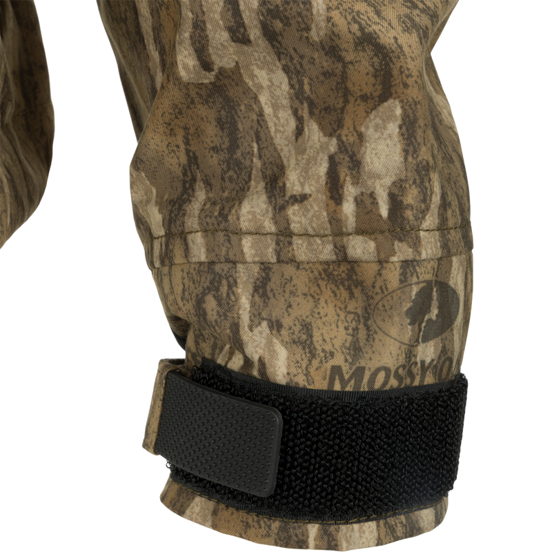 Close-up of G3 Flex Uninsulated Waterfowlers Jacket's camouflage sleeve, black strap, and patch, highlighting its rugged, waterproof fabric and durable design.