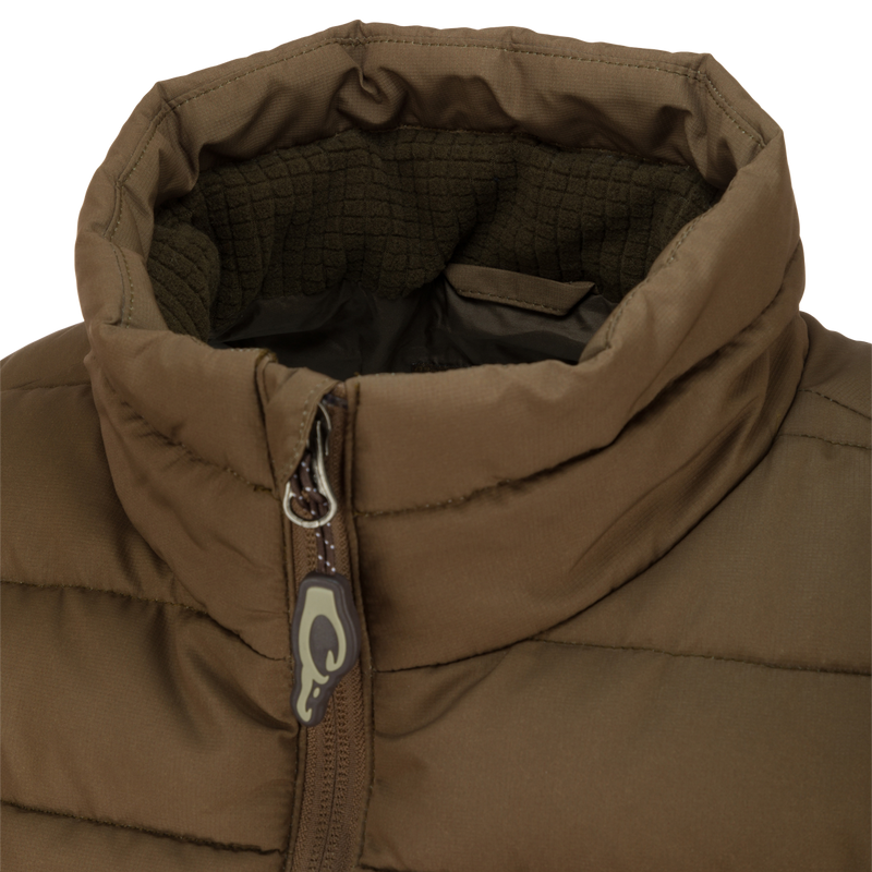 Close-up of the LST Double Down Layering Vest showcasing the zipper and logo, highlighting its durable, insulated design and microfleece-lined collar for added warmth.