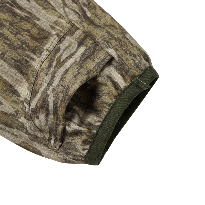 Close-up of the Half Zip Pullover with Spider Web Technology, showcasing the camouflage fabric and ergonomic thumbholes designed for turkey hunting.