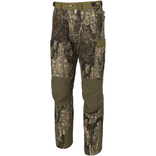 Youth Tech Stretch Turkey Pant, camouflage pattern, shown standing. Features include reinforced knees, adjustable waistband, mesh pockets, and cargo pockets for storage. Designed for durability and comfort.