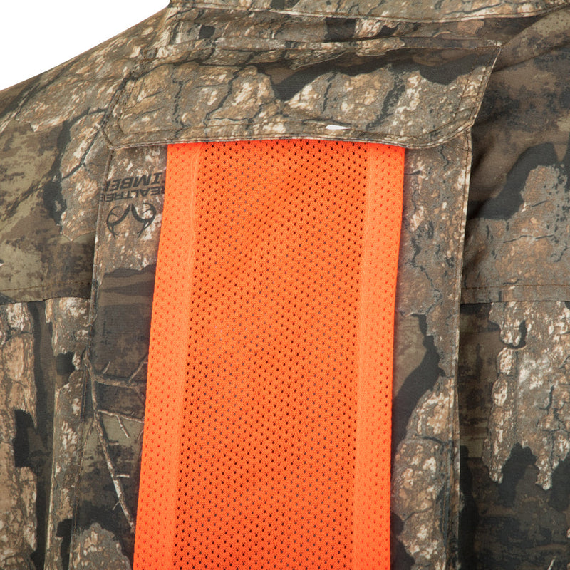 A close-up of the Tech 1/4 Zip with Spine Pad, a camouflage jacket with orange mesh accents. Features include a quarter-zip neck, multiple pockets, and a removable spine pad for added comfort. Perfect for outdoor activities.