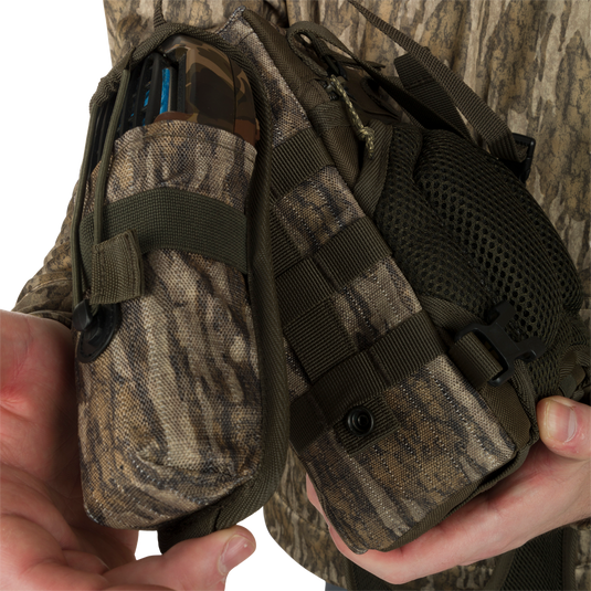 Run-N-Gun Turkey Chest Pack held by a person, featuring a lightweight design with multiple pockets, loops, a detachable bino harness, and a stowable rain fly.