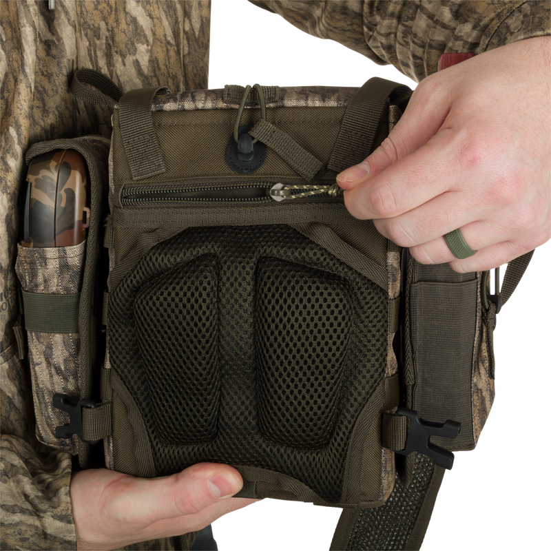 Run-N-Gun Turkey Chest Pack held by person, showcasing durable design with multiple pockets, removable bino harness, and secure zippered compartments.