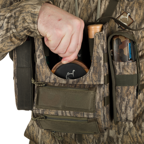 Run-N-Gun Turkey Chest Pack held by person, showcasing its multiple pockets, straps, and compact design, ideal for hunting trips with a detachable bino harness.