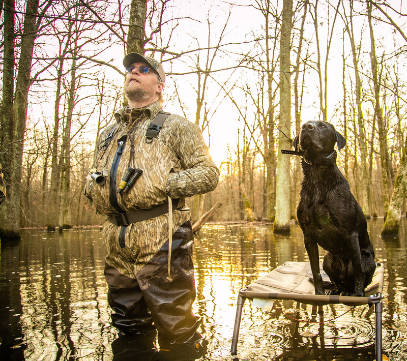 Man wearing LST Double Down Jac-Shirt in water with dog, showcasing its practical pockets and water-resistant fabric for hunting or outdoor activities.