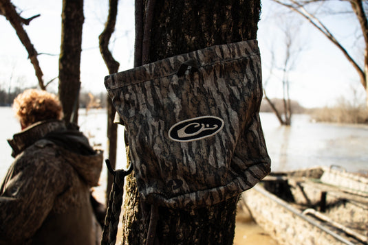 Waterfowler's Shell Bag hanging on a tree, showcasing its durable construction and practical webbing loops for easy hanging and secure grip.