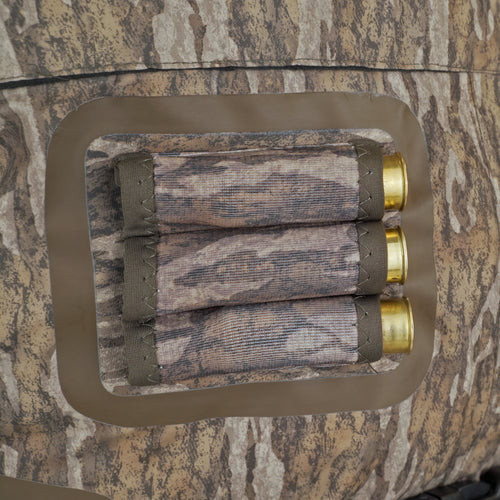 Close-up of Drake Youth Eqwader 1600 Breathable Wader with Tear-Away Liner, featuring durable fabric and shotgun shells on a camouflage mat.